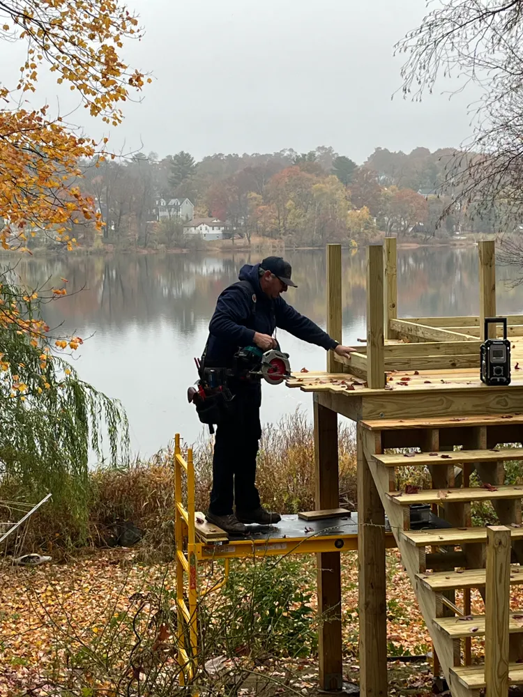 A carpenter framing a deck beside a pond