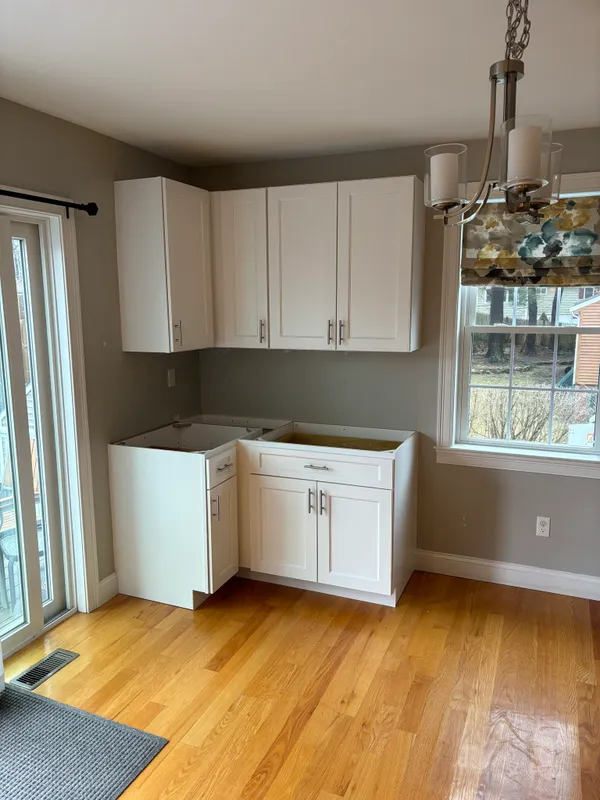 A kitchen with white cabinets beside a window